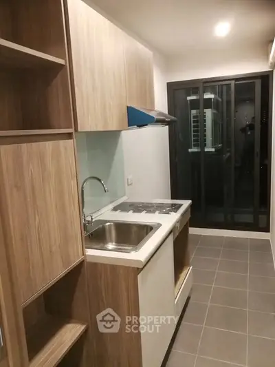 Modern kitchen with sleek cabinetry and sliding glass doors leading to a balcony.