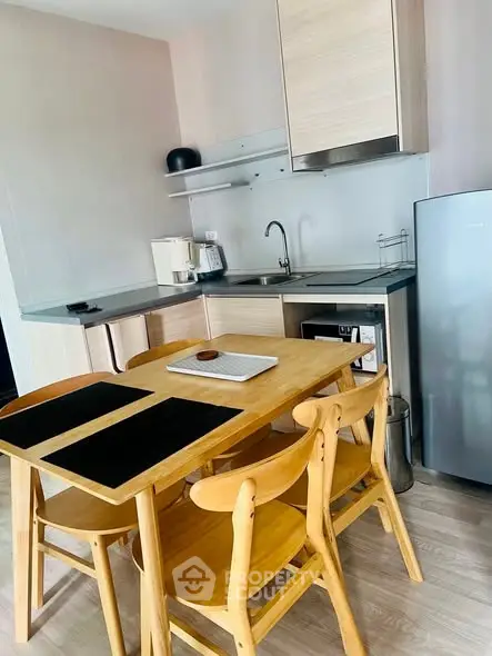 Modern kitchen with wooden dining set and sleek appliances in a cozy apartment.