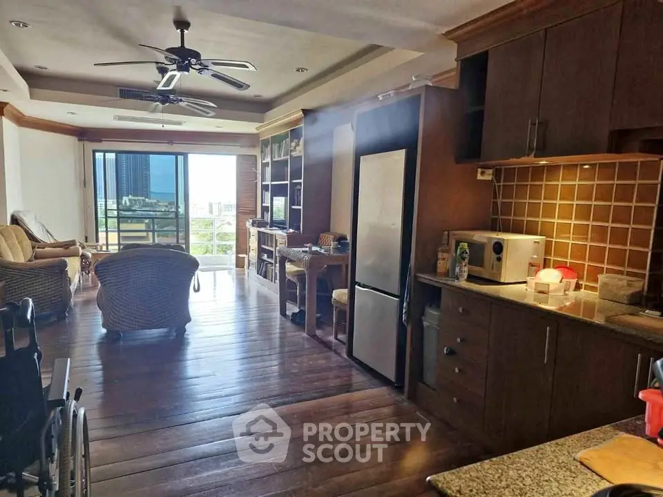 Spacious living room with open kitchen and balcony view in modern apartment.