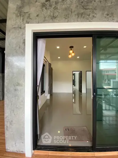 Modern interior with sliding glass door and polished floors, showcasing contemporary lighting and spacious design.
