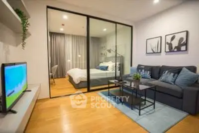 Modern living room with glass partition to bedroom, stylish decor, and cozy seating area.
