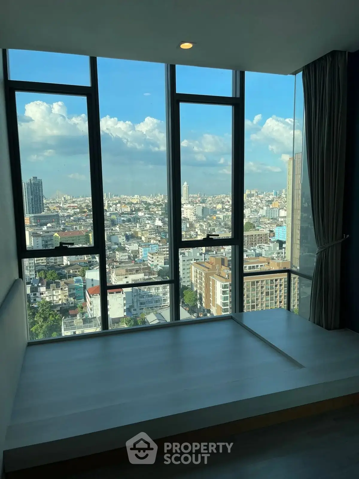 Stunning city view from high-rise apartment with floor-to-ceiling windows.