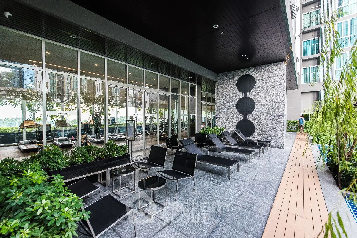Modern outdoor gym area with sleek design and poolside seating in luxury apartment complex.