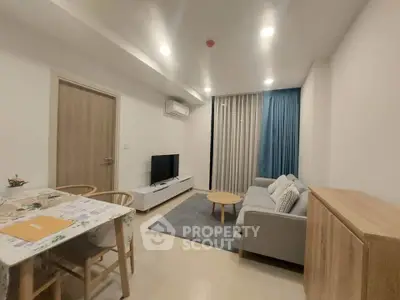 Modern living room with cozy sofa, TV, and dining area in a stylish apartment.