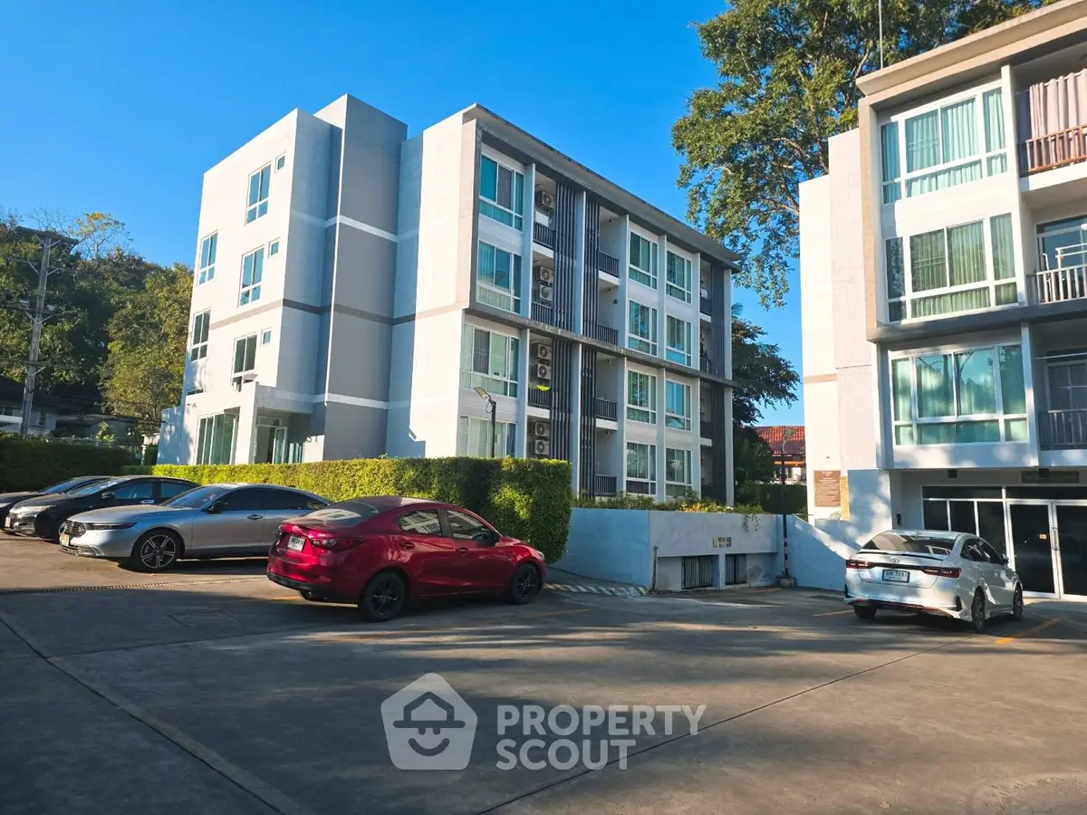 Modern apartment building with parking area and lush greenery