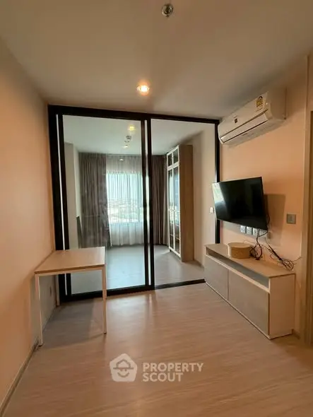 Modern living room with glass partition and wall-mounted TV in stylish apartment.