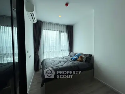Cozy bedroom with large window and modern decor, perfect for relaxation and comfort.