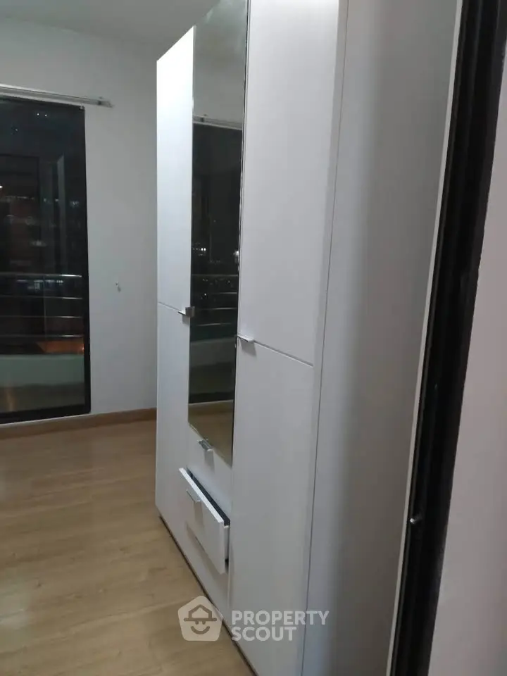 Modern wardrobe in a sleek bedroom with wooden flooring and balcony view.