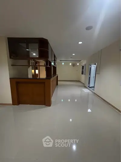 Spacious open layout living area with glossy tiled floors and modern wooden cabinetry.