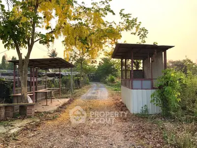 Charming rural pathway with rustic structures and lush greenery, perfect for serene countryside living.
