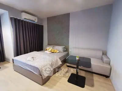 Modern bedroom with stylish decor, featuring a cozy bed, elegant sofa, and sleek table in a well-lit space.