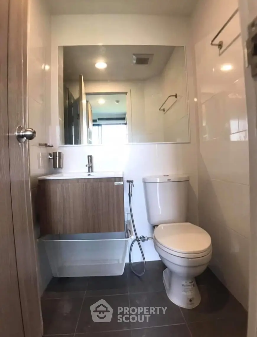 Modern bathroom with sleek fixtures and large mirror in a compact space.
