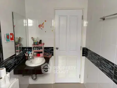 Modern bathroom with stylish black tile accents and sleek vanity mirror