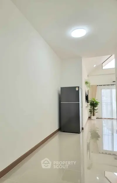 Spacious modern interior with sleek refrigerator and large windows for natural light.