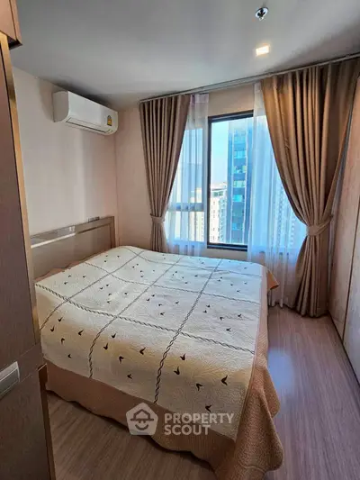 Cozy bedroom with large window and city view, featuring elegant curtains and modern air conditioning unit.