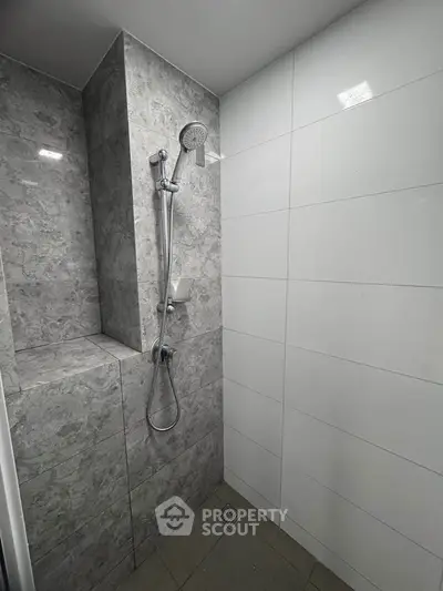 Modern bathroom shower area with sleek gray tiles and contemporary fixtures.