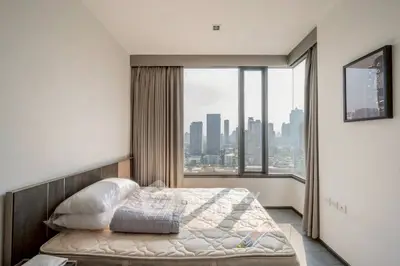 Modern bedroom with city view, featuring large windows and stylish decor.