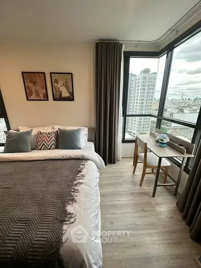 Modern bedroom with city view, featuring cozy bed and stylish decor in high-rise apartment.