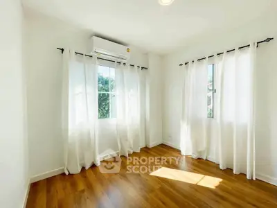 Bright and airy room with wooden flooring and large windows, perfect for a cozy living space.