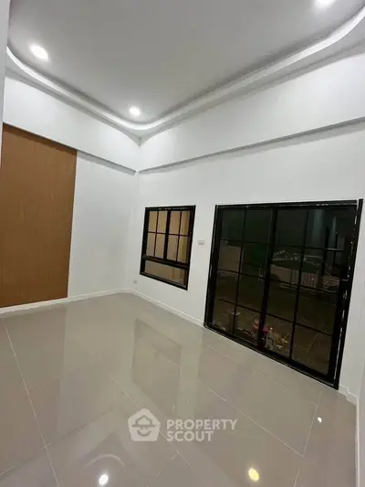 Spacious modern living room with sleek tile flooring and large windows for natural light.