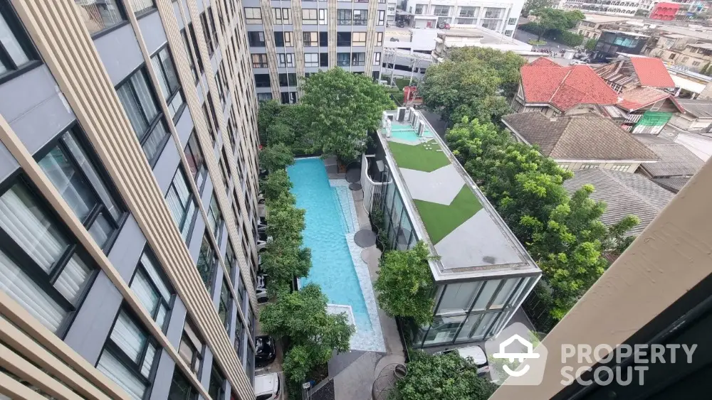 Stunning aerial view of modern apartment complex with pool and lush greenery.