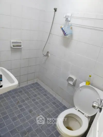Compact bathroom with tiled walls and floor, featuring a shower and toilet.