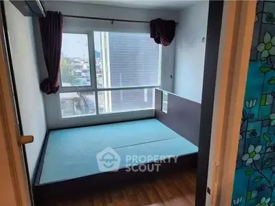 Spacious bedroom with large window and wooden flooring in modern apartment