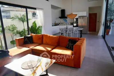 Modern living room with orange sofa, open kitchen, and large windows in a stylish home.