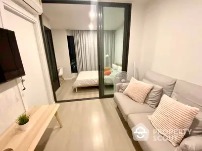 Modern apartment with sleek furnishings featuring a cozy living room with a comfortable sofa and a bedroom view through a large glass partition.