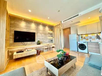 Modern living room with stylish decor and open kitchen layout, featuring a washing machine and fridge.