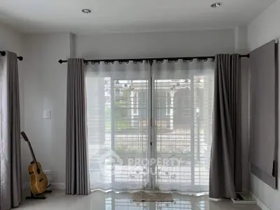 Spacious living room with large windows and elegant curtains, perfect for natural light.
