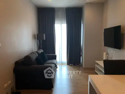 Modern living room with cozy sofa and wall-mounted TV, featuring elegant curtains and wooden flooring.