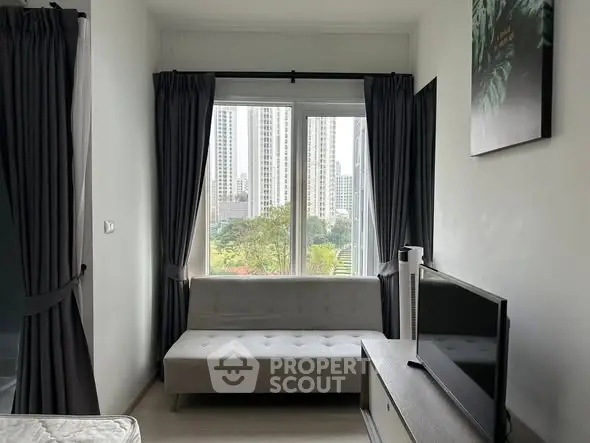 Modern living room with city view, featuring sleek furniture and large window for natural light.