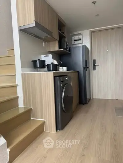 Modern compact kitchen with wooden cabinetry and integrated appliances in a stylish apartment.