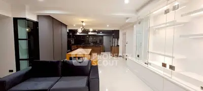 Spacious modern living room with open kitchen and stylish lighting fixtures.