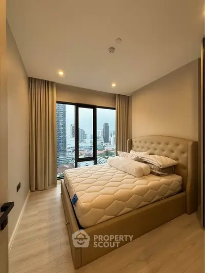 Modern bedroom with city view, featuring a plush bed and large windows in a high-rise apartment.