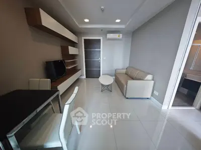 Modern living room with sleek furniture and neutral tones, featuring a TV and dining area.