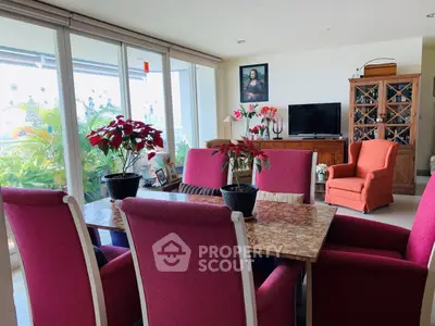 Charming living room with vibrant pink chairs, elegant dining table, and lush greenery view.