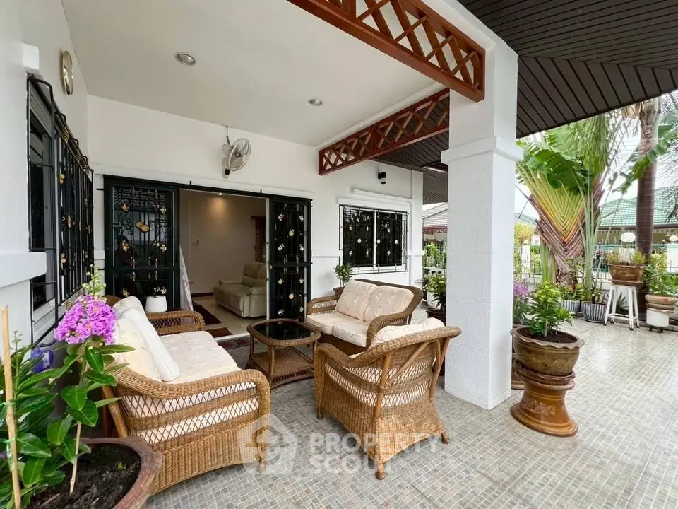 Charming outdoor patio with wicker furniture and lush garden view, perfect for relaxation.