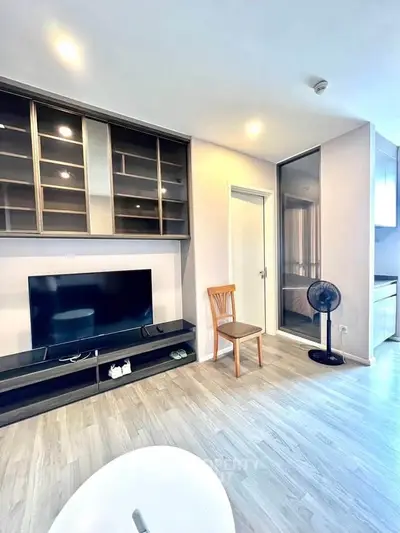 Modern living room with sleek TV unit and glass cabinet, featuring light wood flooring and contemporary decor.