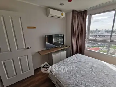 Cozy bedroom with large window offering city views, featuring a mounted TV and air conditioning for comfort.