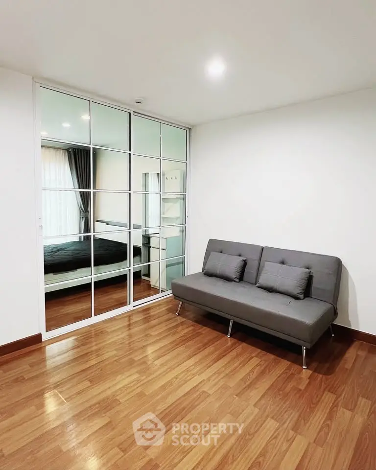 Modern living room with sleek sofa and mirrored sliding doors in a stylish apartment.