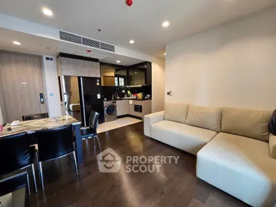 Modern living room with open kitchen, featuring sleek furniture and hardwood floors in a stylish apartment.