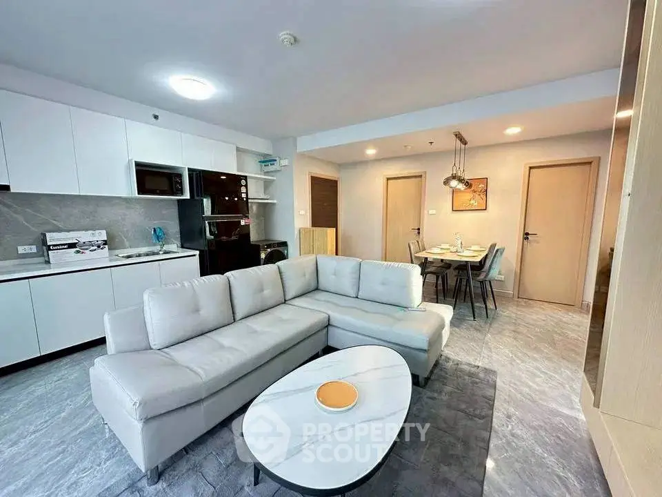 Modern open-layout living room with sleek kitchen and dining area, featuring stylish furniture and contemporary design.
