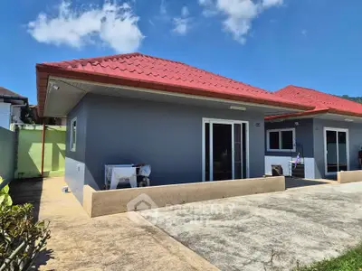 Charming single-story home with red roof and spacious patio under clear blue skies.