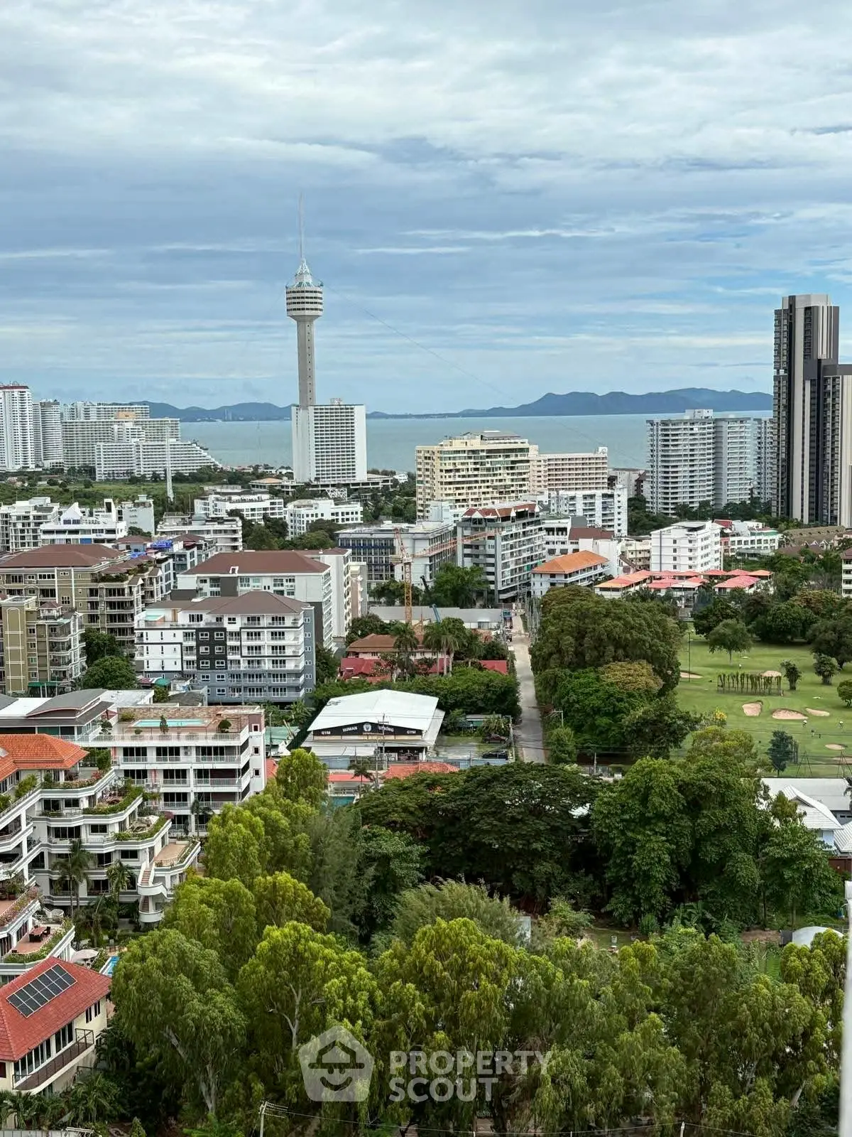 Stunning cityscape view with lush greenery and ocean backdrop, ideal for urban living.