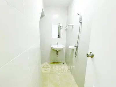 Minimalist bathroom with white tiles and modern fixtures in a sleek real estate property.