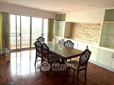 Spacious dining area with elegant wooden furniture and large windows offering a scenic view.
