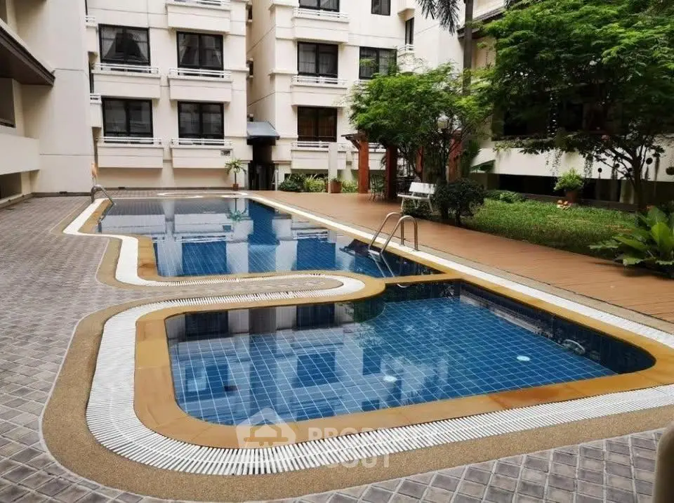 Luxurious residential building with pristine swimming pool and lush garden area.