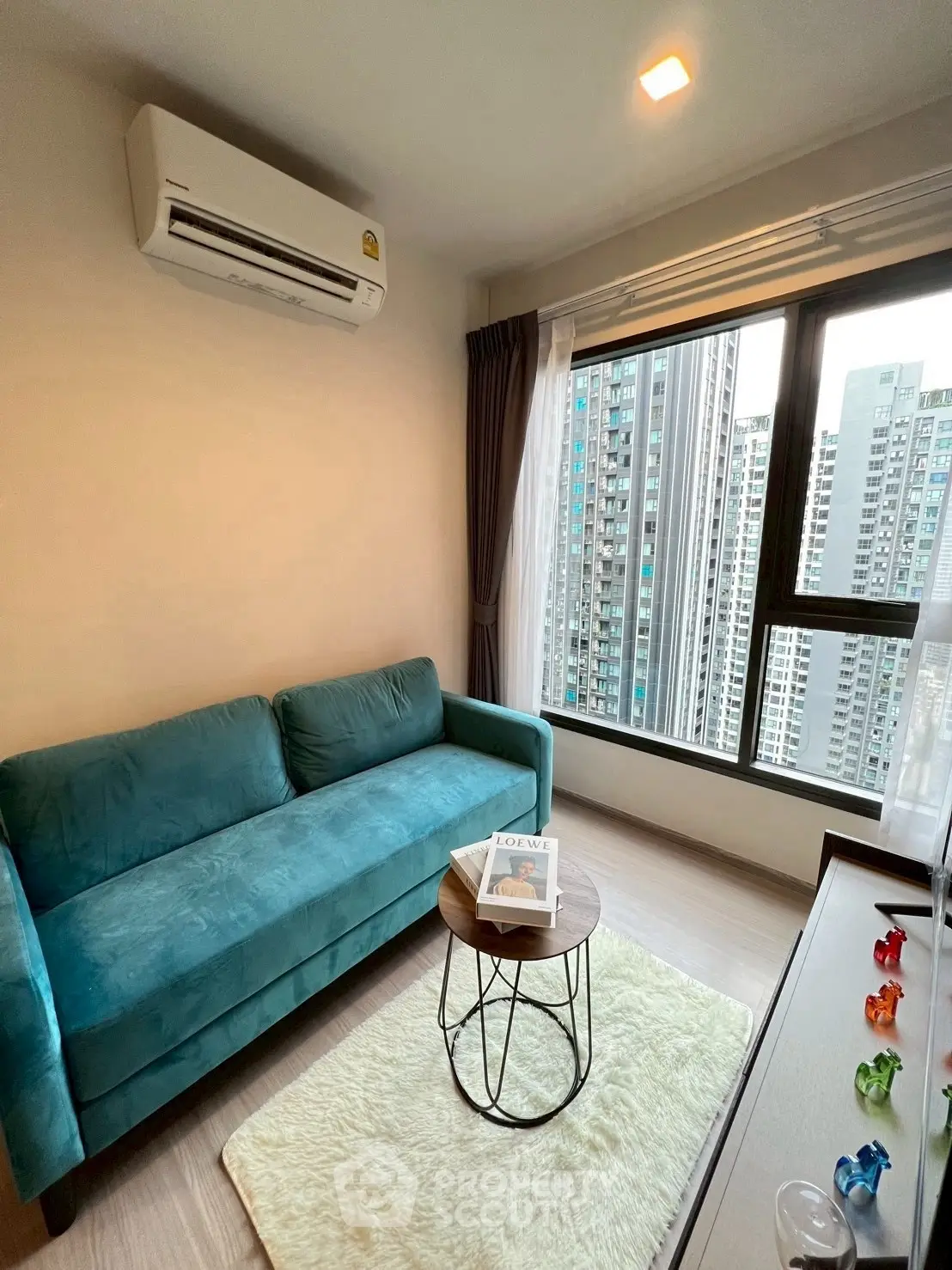 Modern living room with teal sofa and city view, perfect for urban living.